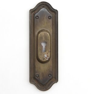 Traditional brass-plated steel pocket door plate with a recessed keyhole and four screw holes, shown front-on with worn finish and decorative arched ends.