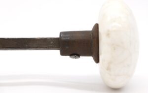 Close-up of a white crackled ceramic door knob with a dark metal shank and spindle.