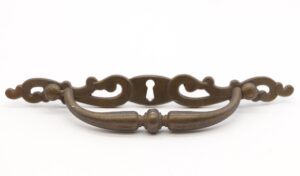 Pair of traditional brass drawer pulls with keyhole backplates and curved handles, shown as a matching pair with visible surface wear and screw holes.