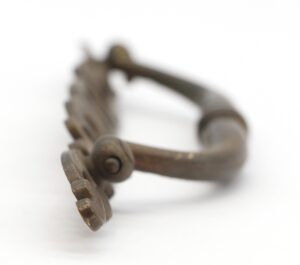 Pair of traditional brass drawer pulls with curved handles and keyhole backplates, shown in a close-up view with mounting screws visible on one pull.