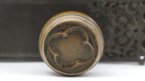 Close-up of an antique bronze door knob with a Gothic quatrefoil face and aged blackened finish.