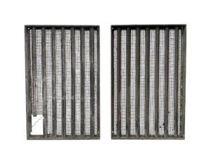 Pair of bronze window grates with woven brass mesh, shown side by side, with a small cutout in the lower corner of one grate.
