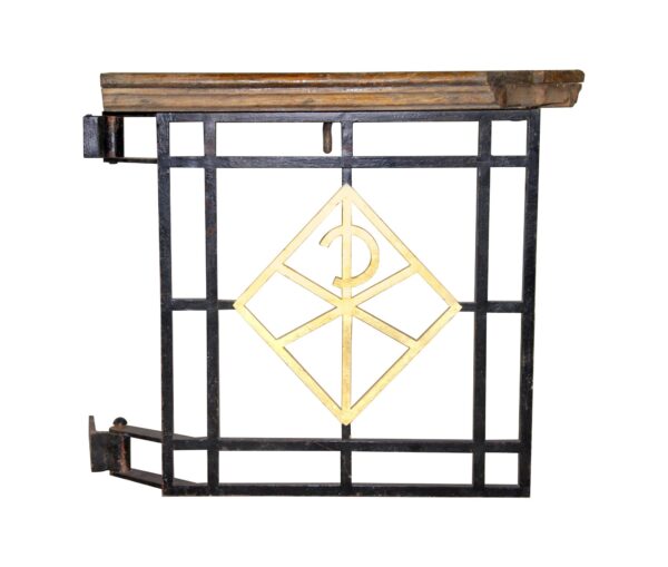 Ecclesiastical wrought iron gate with a dark wood-toned top rail and a gold religious insignia at the center.