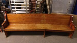 Extra long oak pew with a simple backrest and seat in a dark wood tone, shown from the front.