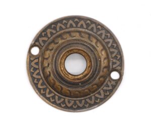 Antique brass door rosette with a radial pattern and two mounting holes.