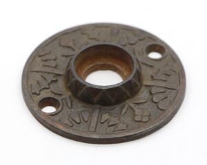 Round cast iron door rosette with an ornate floral Aesthetic pattern and two screw holes.