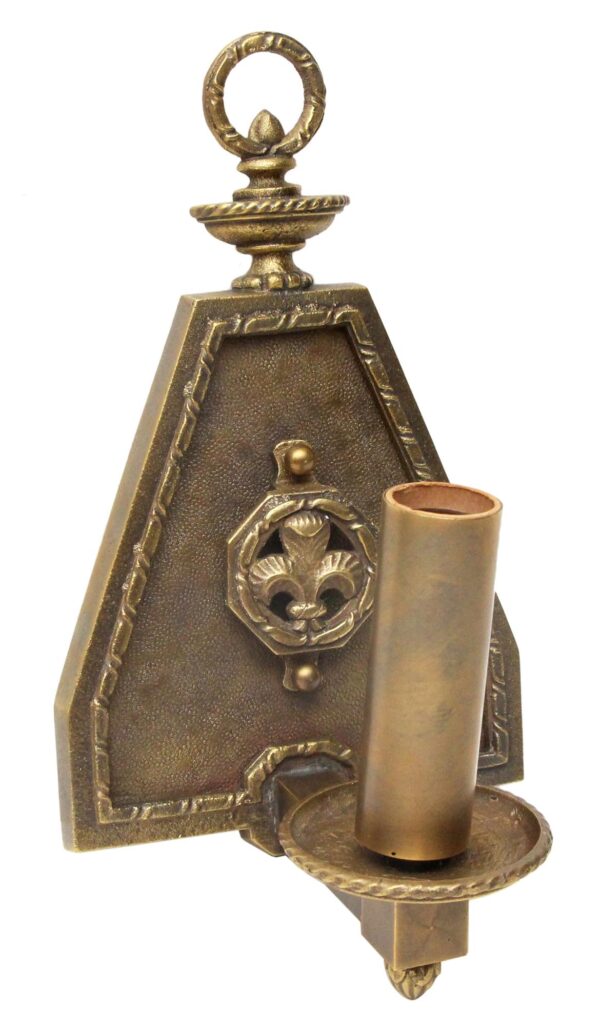Antique brass wall sconce with one arm, a fleur de lis center motif, and raised decorative edges.