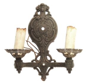 Ornate Victorian two-arm wall sconce in black metal with candle-style holders and decorative backplate.