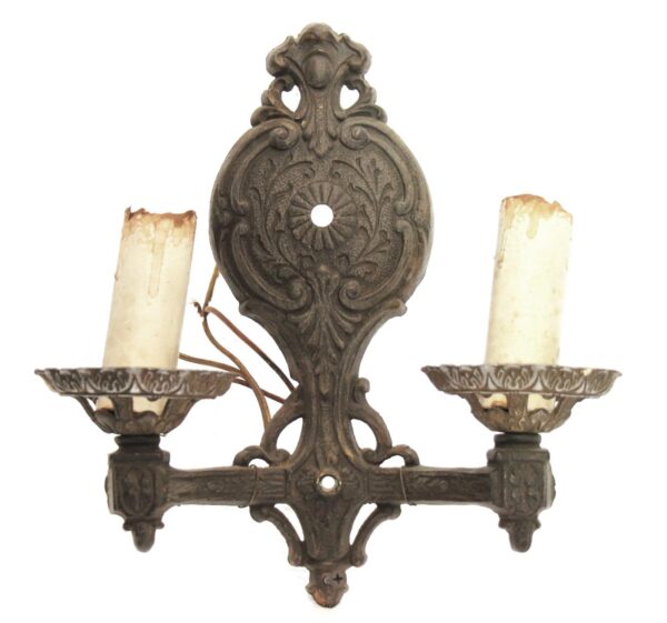 Ornate Victorian two-arm wall sconce in black metal with candle-style holders and decorative backplate.