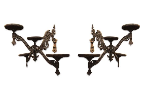 Pair of Victorian cast iron lamp holders with four arms and ornate scrollwork, shown in a symmetrical front view.