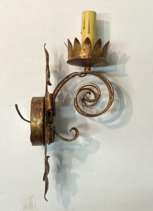 Gothic wall sconce in gilded wrought iron with a scrollwork arm, decorative leaf details, and a candle-style holder.