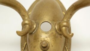 Close-up of an antique bronze Empire wall sconce showing the central backplate and two curved arms with candle sockets.