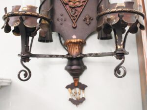 Pair of Tudor-style two-arm wall sconces with ornate bronze and wrought iron details, shown together in a close-up view with aged black and antique bronze finish.