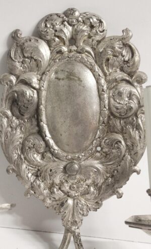 Ornate Rococo wall sconce in silver finish with a floral and foliage frame and an oval center plate.