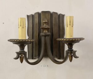 Pair of traditional bronze wall sconces with an antique bronze finish, each with two candle-style arms and ribbed cylindrical candle sleeves.