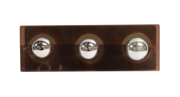 Mid century modern brown lucite wall sconce with three mirrored bulbs arranged in a horizontal row.