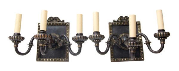 Pair of Tudor-style two-arm wall sconces with two candle-shaped bulbs each, shown as a matching set with ornate backplates and black and gold finish.