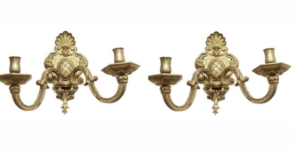 Pair of antique brass French two-arm wall sconces with ornate scrollwork and candle-style holders, shown as a matching pair.