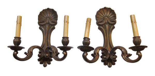 Pair of neoclassical two-arm wall sconces in antique bronze, shown as a matching pair with decorative scrollwork and candle holders.