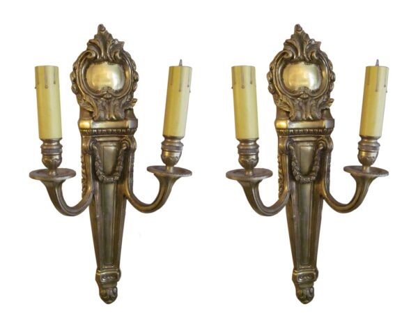 Pair of Louis XVI style brass wall sconces with two arms each and candle-shaped lights.