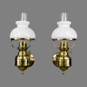 Pair of French-style wall sconces in polished brass with white glass shades and clear glass chimneys, shown as a matching pair.