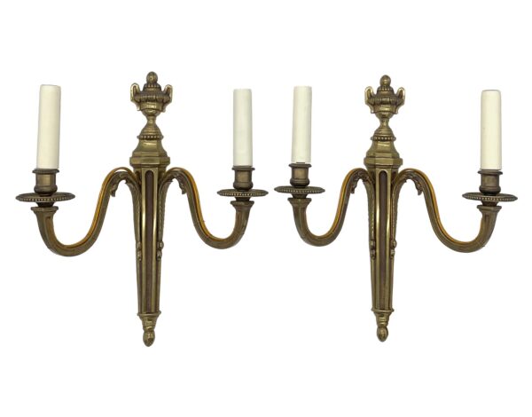 Pair of French bronze double arm wall sconces with urn finials and six candle sockets shown side by side in a matching pair.