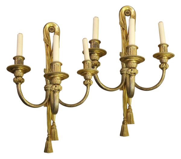 Pair of ornate French three-arm wall sconces with gilded bronze finish and candle-style holders, shown as a matching pair.