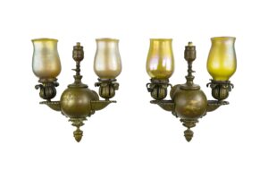 Pair of Victorian brass two-arm wall sconces with iridescent glass shades, shown as a pair with one shade slightly different.