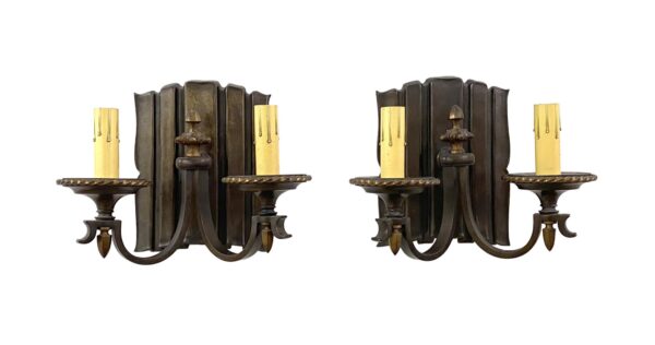 Pair of traditional two-arm wall sconces in antique bronze finish, shown front-facing with ornate candle-style holders and curved arms.