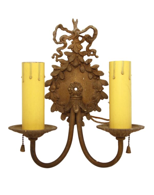 Ornate Victorian two-arm wall sconce in antique brass with beaded ribbon detailing and two candle-style sockets.