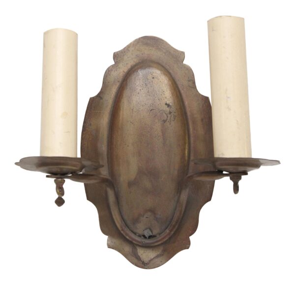 Traditional two-arm brass wall sconce with an antique brass finish and two candle-style sockets, shown front view.