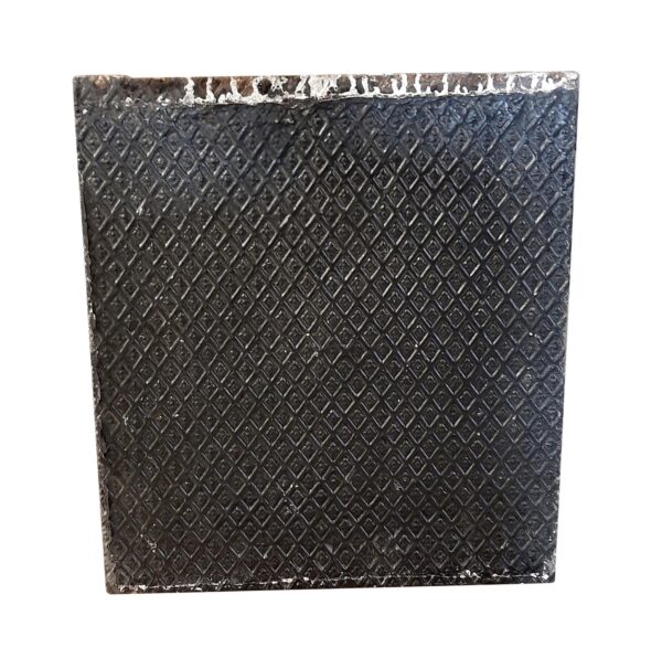 Black cast iron fire back piece with a diamond-textured surface and worn top edge, shown front on.