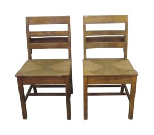 Pair of square antique schoolhouse chairs with light wood tone frames and hand-caned seats, shown front view.