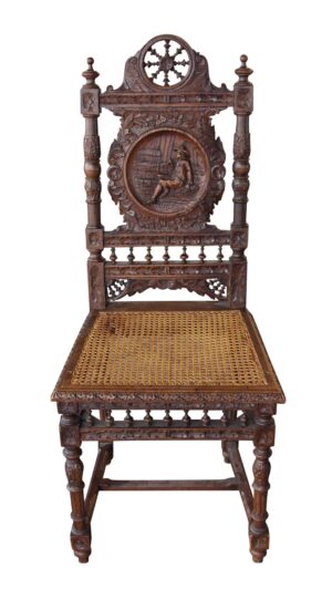English Renaissance carved wooden chair with a wicker seat and an ornate back featuring a round figural carving.