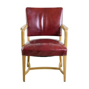 Front view of a mid century modern armchair with a dark red leather seat and back, light wood tone oak arms and frame, and visible wear with light cracking on the seat.