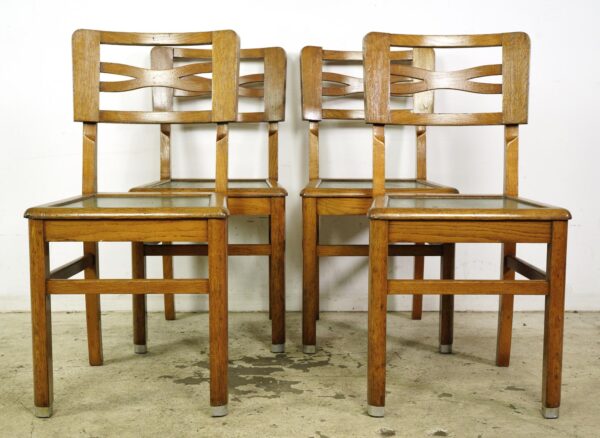 Set of four vintage wood dining chairs with green upholstered seats, shown front view in two rows.