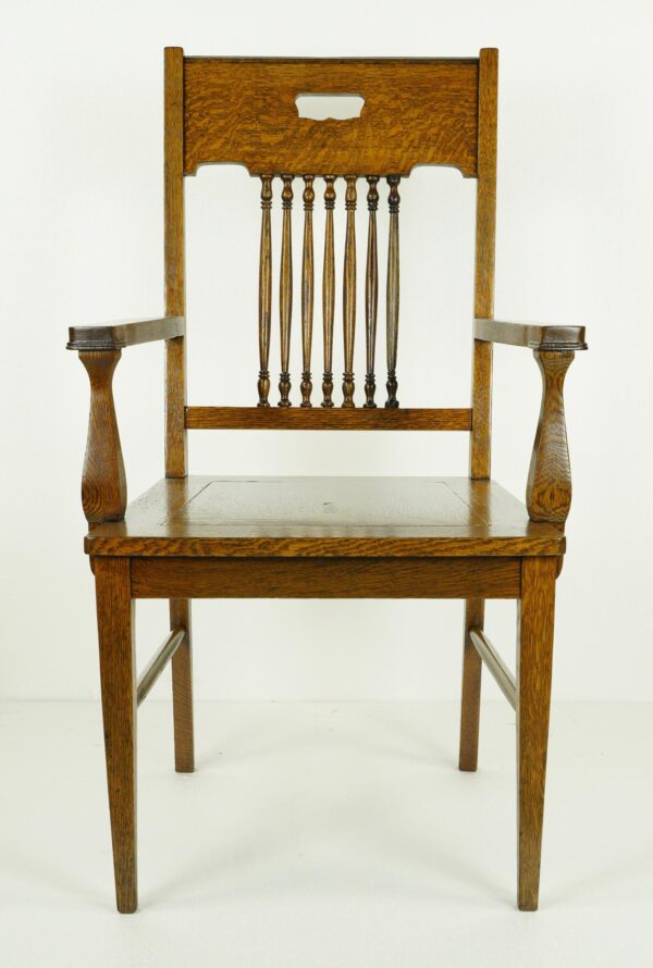 Traditional oak arm chair with spindle back, arms, and dark wood tone finish shown from the front.