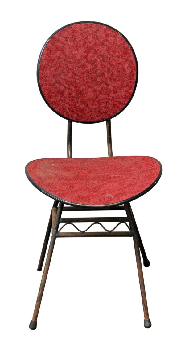 Vintage chair with a round back and curved seat, shown in red and black with a black metal frame and textured plastic seat and back.