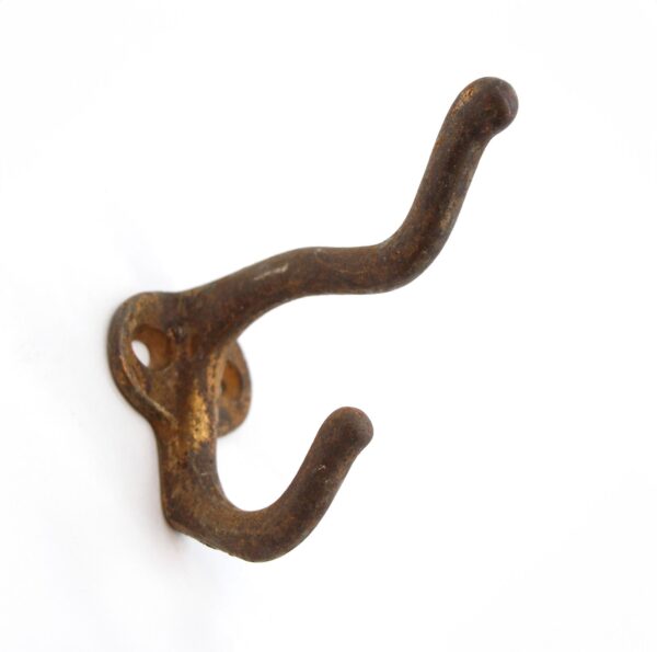 Antique cast iron double arm wall hook with an antique bronze finish, shown close up with visible rust and two curved hooks.