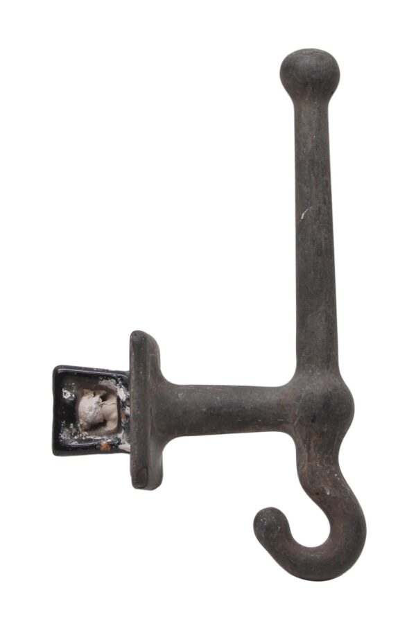 Antique cast iron flush mount wall hook with a heavy industrial design and curved hook end.