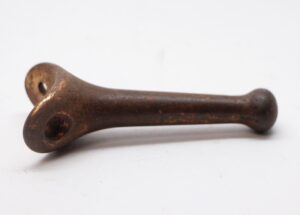 Cast iron peg hook with an antique bronze finish, shown in profile with a mounting hole at one end and surface wear from prior use.