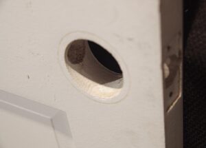 Close-up of a white wooden closet door showing the oval handle cutout and edge of the panel, with no hardware included.