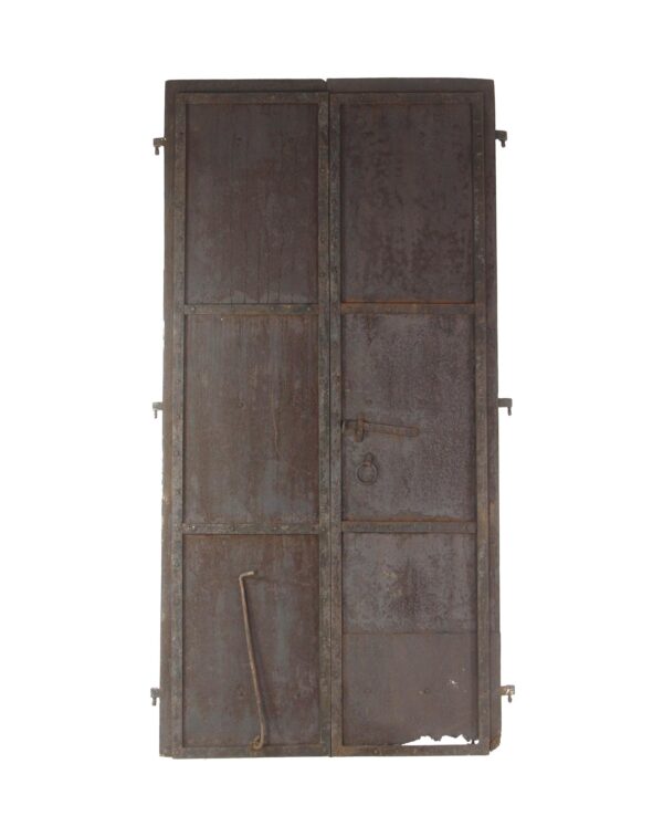 Pair of antique cast iron shutter doors with three panels, showing original strap hinges, a natural rust patina, and visible wear from age and use.