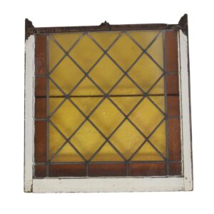 Antique stained glass window with amber and brown panes in a white-painted wood frame, shown front view.
