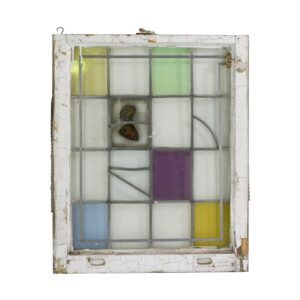 Wood-framed stained glass window with pastel blue, clear, purple, red, and yellow panes and a small coat of arms detail near the top, shown front on with visible surface wear.
