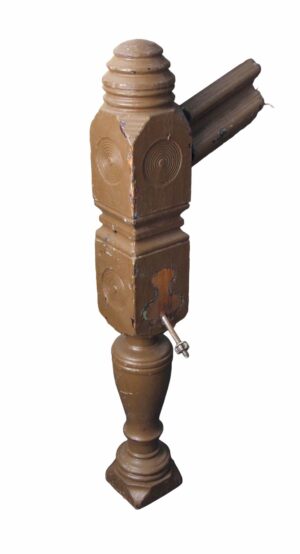 Traditional carved wood staircase newel post with bull's eye details and visible wear, shown in a close-up view with one side and the turned base.
