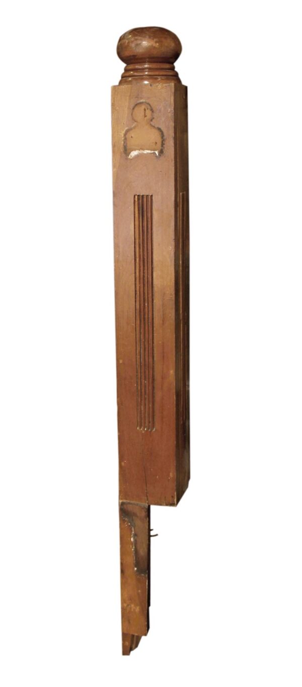 Tall antique wood staircase newel post with a dark wood tone and a rounded top, shown in a side view with a carved decorative detail near the upper section.