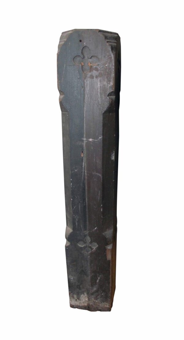Tall antique wooden staircase newel post with a carved Gothic cross detail and a dark painted finish shown in a vertical close-up.