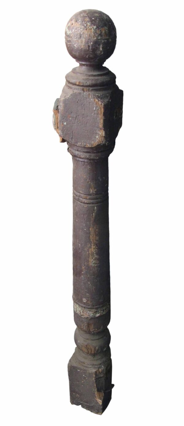 Antique traditional wooden staircase newel post with a carved ball tip and visible wear.