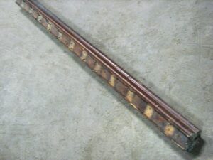 Reclaimed wooden banister handrail shown diagonally in a close-up view, with a dark wood tone and visible wear along the length.